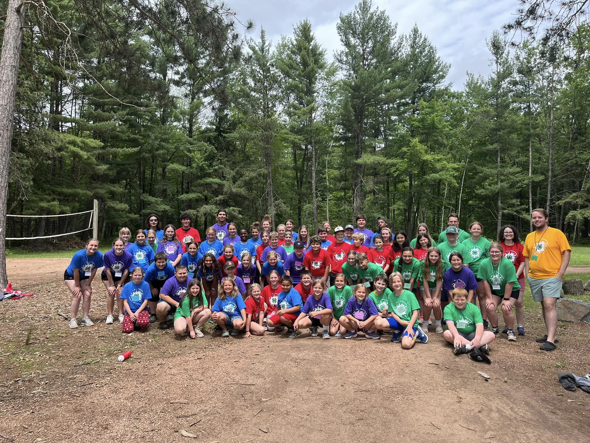 Image of camp participants at camp. Roughly 60 youth members in a variety of colored shirts.