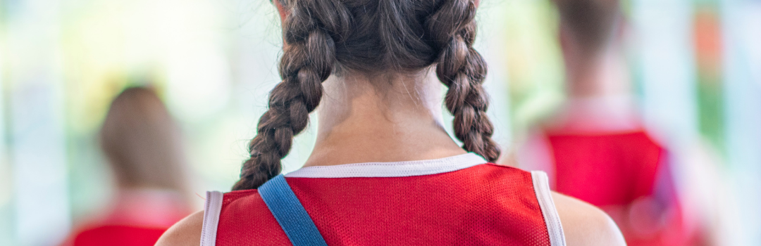 Image of the back of a lifeguard with a red shirt that displays Lifeguard on shirt.
